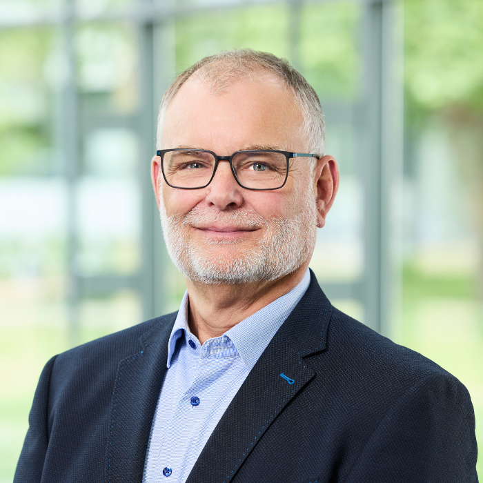 A portrait of a white man, wearing glasses and a suit